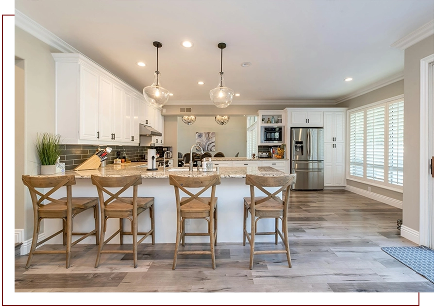 A kitchen with white cabinets and wooden chairs.